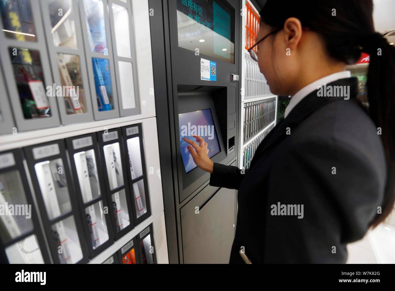 Ein Bürger verwendet, um die Maschine zu Bücher kostenlos vor einem gemeinsamen Bücherregal betrieben von zhima Credit von Alibaba Ant Finanzielle, Shanghai Yangpu ausleihen Stockfoto