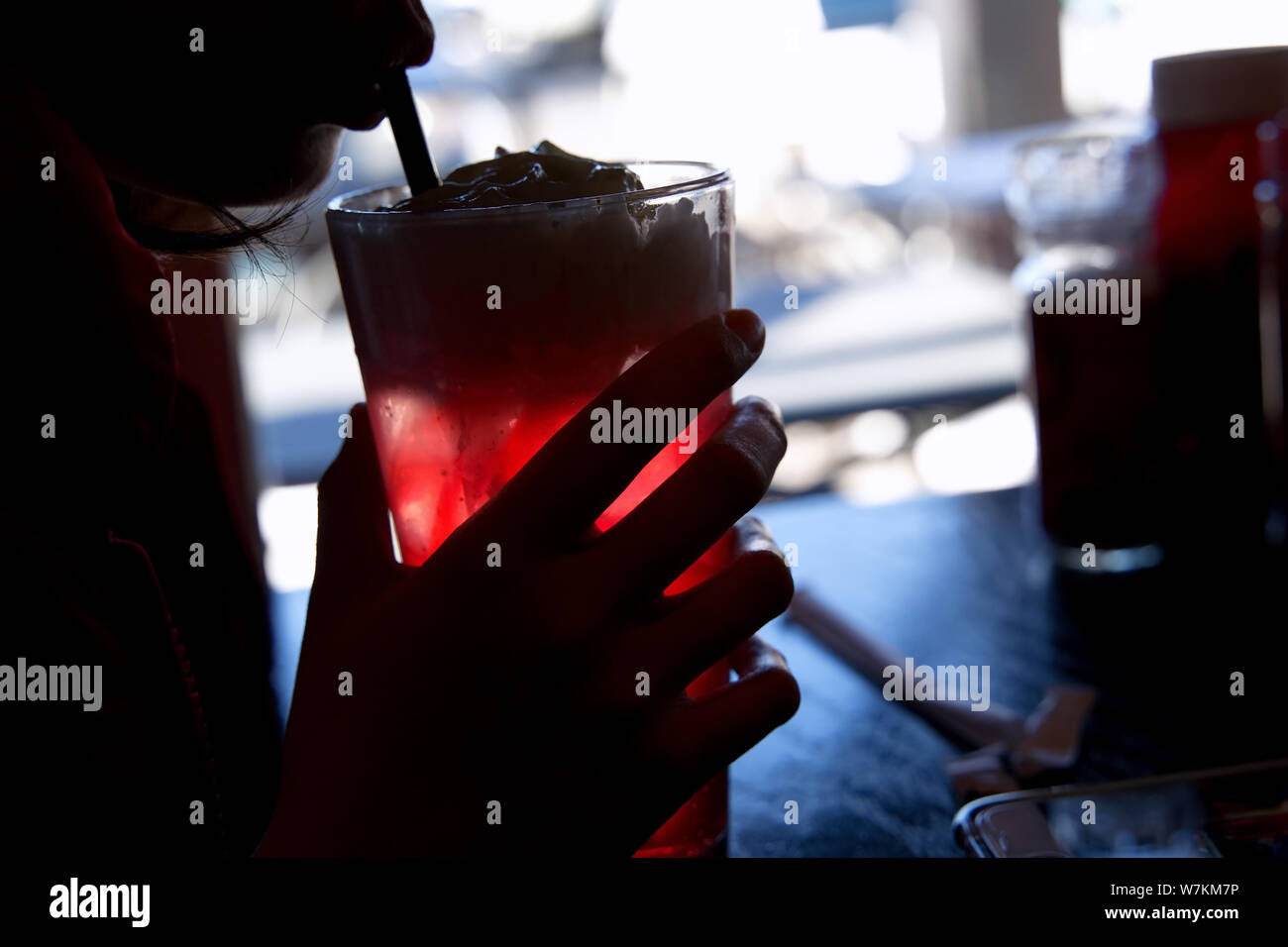 Silhouette von einem eiskalten Cherry Soda Schwimmer in den Händen eines jungen Kunden an Ihr Handy suchen. Stockfoto