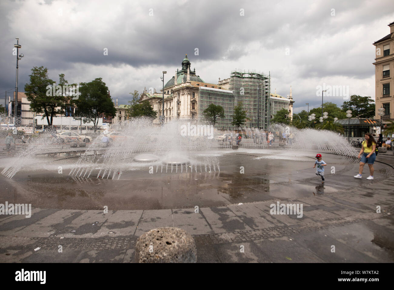 Der Brunnen am Karlsplatz in München, Deutschland, an einem bewölkten Sommertag. Das Landgericht München I Gebäude im Hintergrund. Stockfoto
