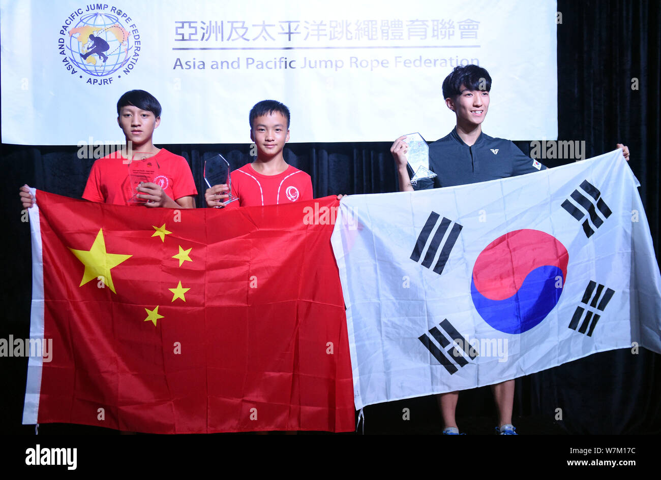 Cen Xiaolin, ein 13-jähriger Junge aus dem Süden Chinas Guangdong, Mitte, seine Trophäe und die Flagge der Volksrepublik China nach Posen Stockfoto