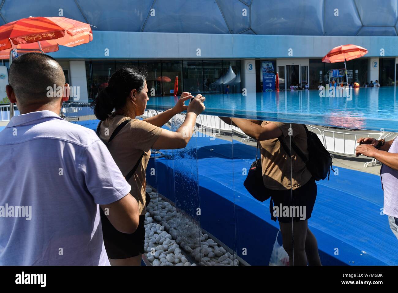 Die Besucher nehmen Fotos der 25 Meter lange und 15 Meter breite Infinity Pool neben dem China National Aquatics Centre, besser bekannt als "Water Cube", in Stockfoto
