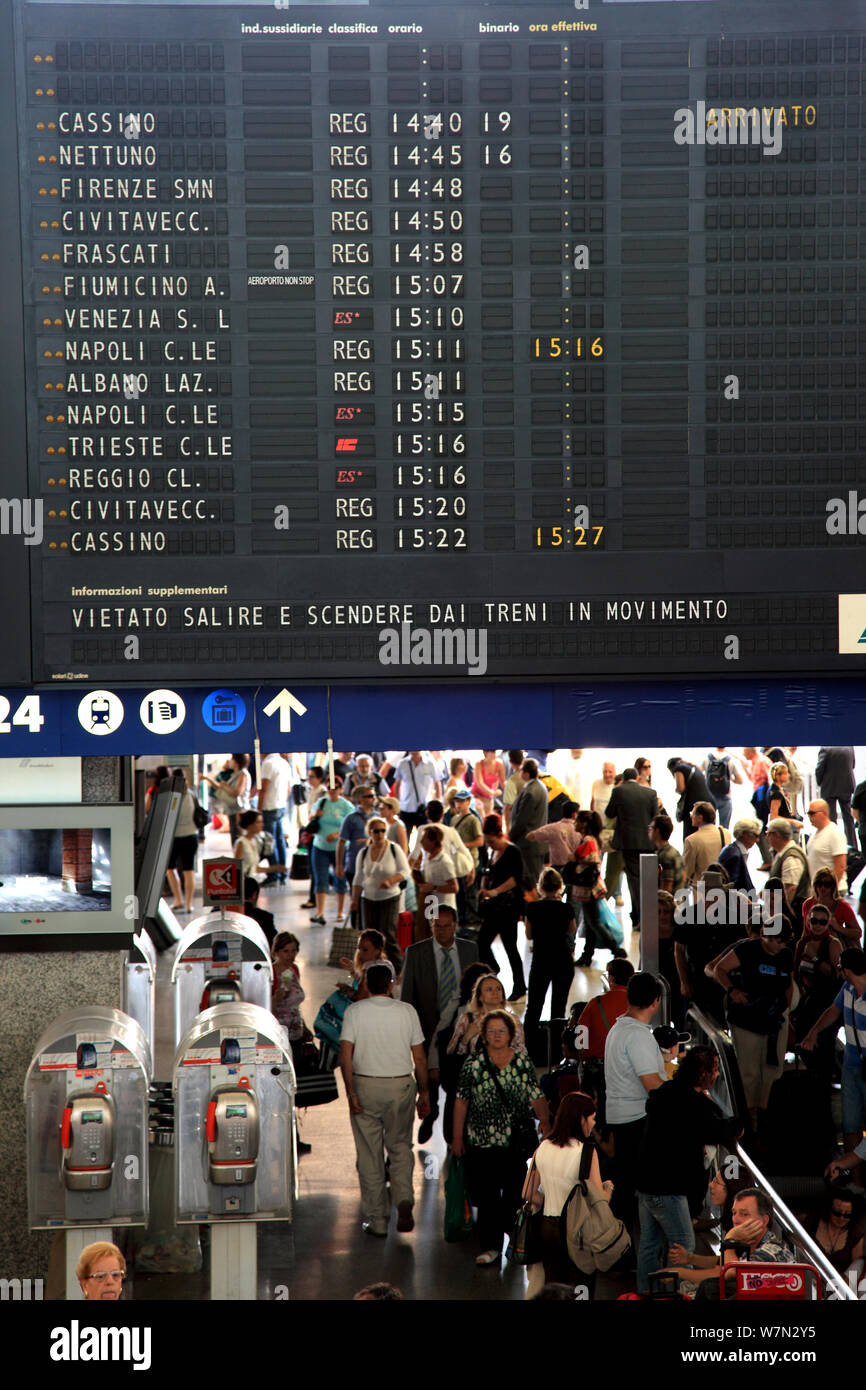 Menschenmassen passieren durch ein Brett mit Abfahrtszeiten zur Stazione Termini in Rom Stockfoto
