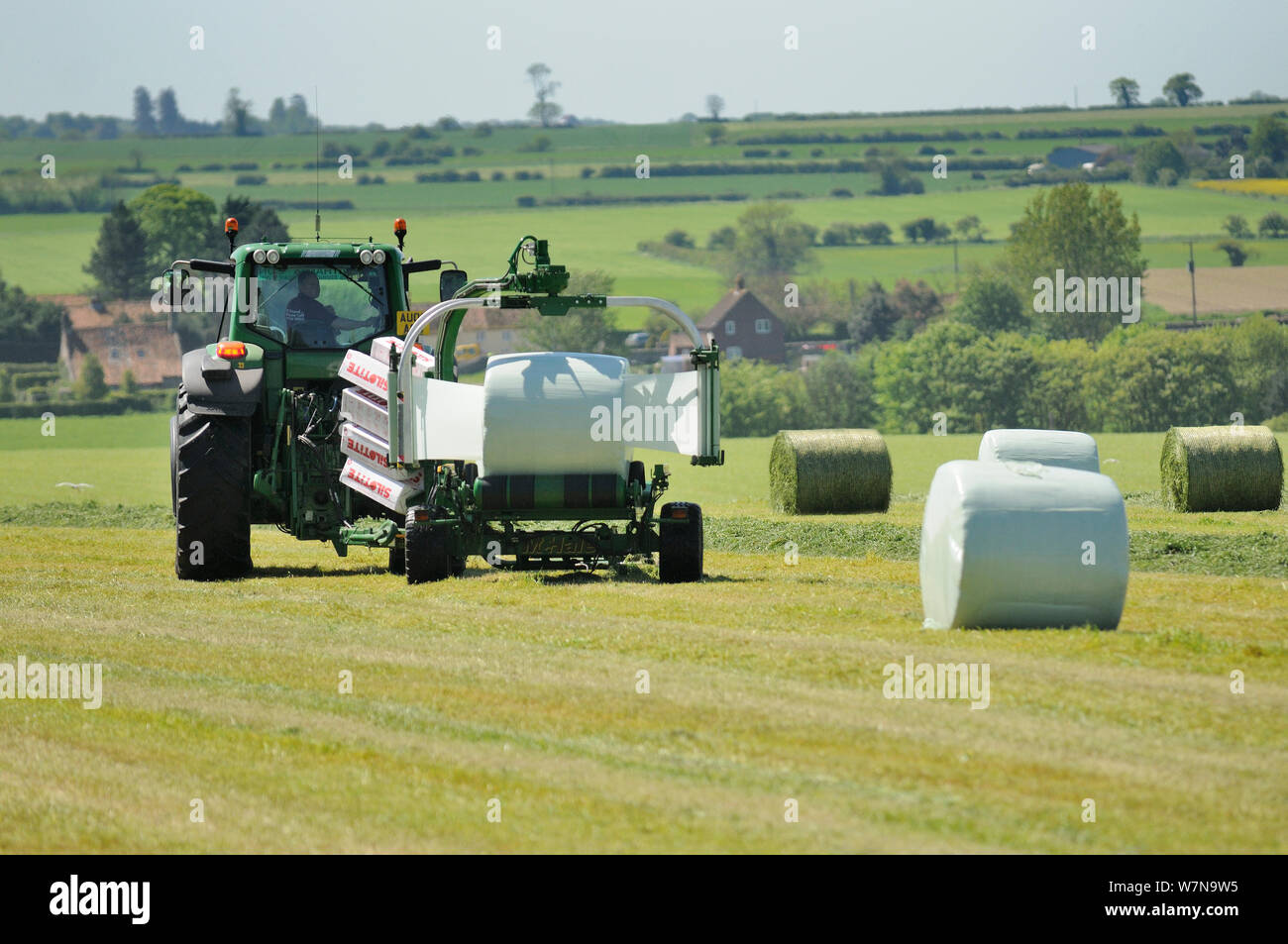Mechanisierte heulage Ernte, Traktor mit Gerät für die Umhüllung von hayage Ballen in Kunststoff, Norfolk, UK, Mai Stockfoto