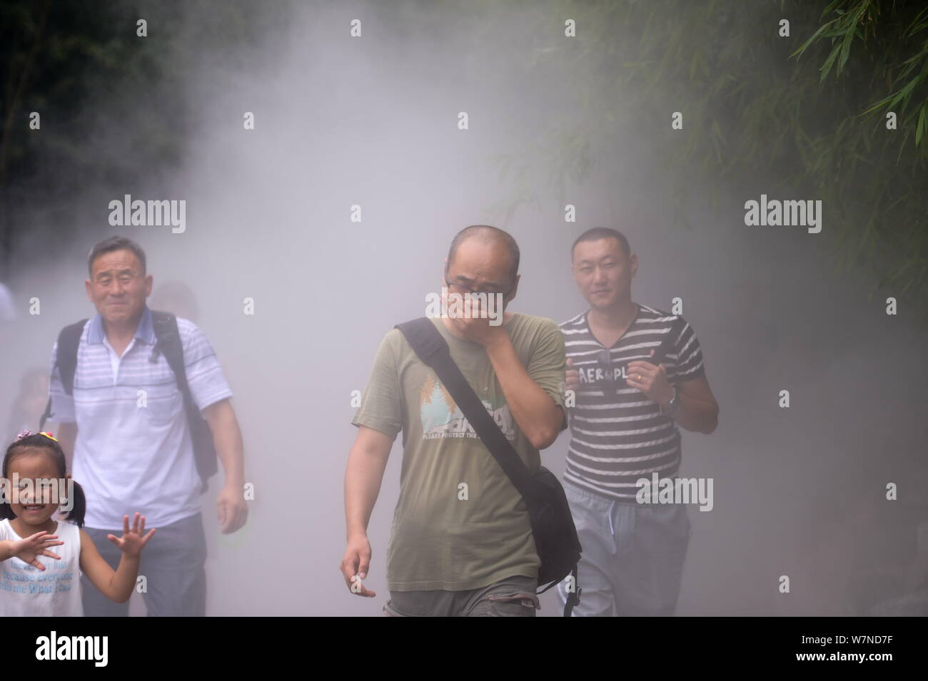 Eine touristische deckt seinen Mund und Nase mit seinen Händen, als er Fehler der Wasserdampf für dichten Rauch eines Feuers an der Beijing Zoo in Peking, China, 25 J Stockfoto