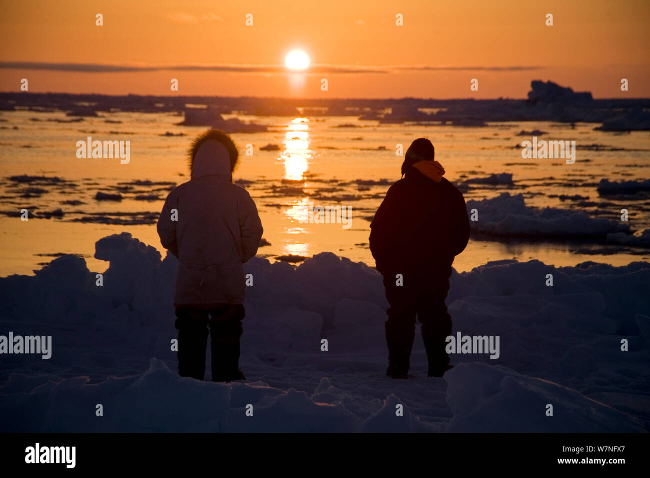 Silhouette der Inupiaq Aufenthaltskosten walfänger am Rande einer Leitungsunterbrechung im Packeis, suchen die bowhead Wale Mitte der Sonne folgt den Horizont. Chukchi Sea, offshore von Barrow, arktischen Küste von Alaska, Mai 2012. Stockfoto