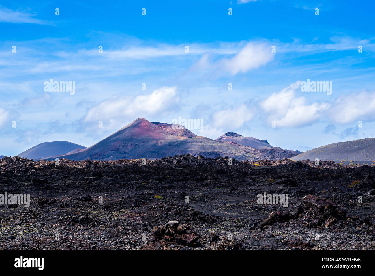 Spanien, Lanzarote, Roten Riesen Vulkan hinter endlosen schwarzen ariden Lavafeld Stockfoto