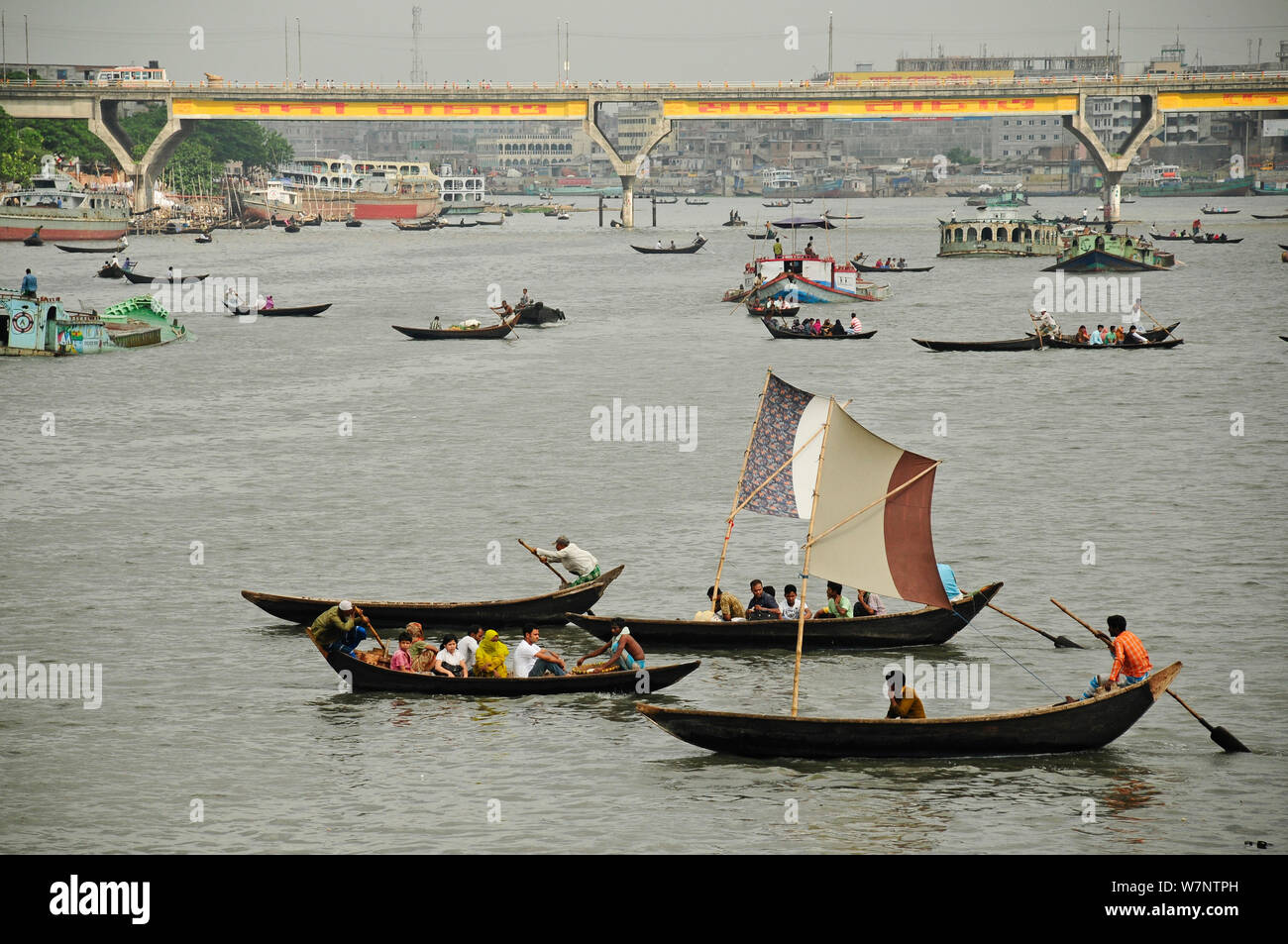 Boote auf dem Wasser, Dhaleshwari Sadarghat Fluss, mit einer Brücke im Hintergrund. Dhaka, Bangladesch, Juni 2012. Stockfoto