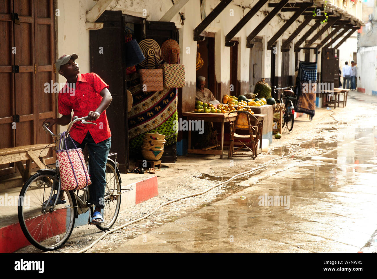 Mann auf dem Fahrrad in der Nähe Shop steht in Stone Town, Sansibar, Tansania, Oktober 2008 Stockfoto