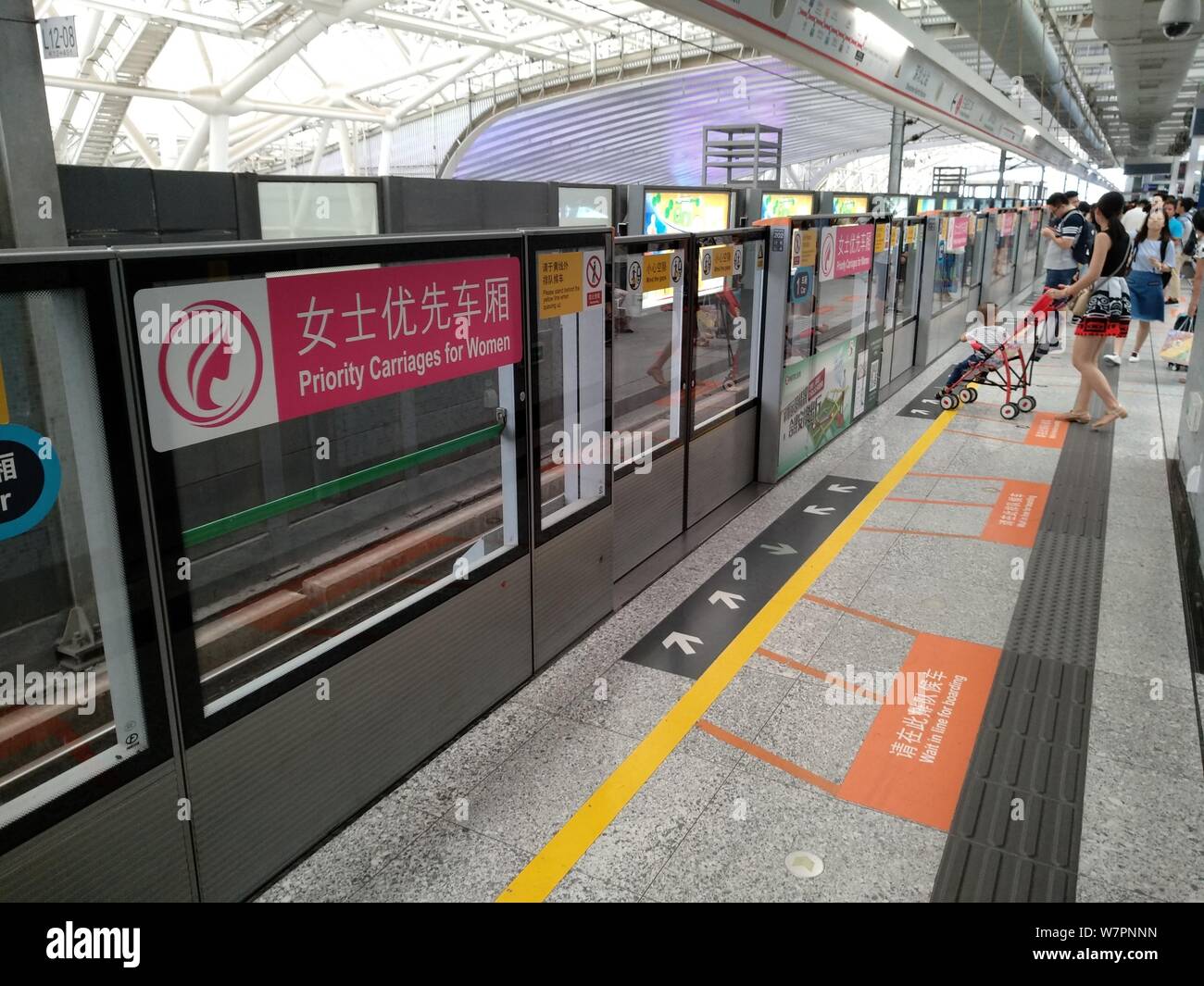 Weibliche Passagiere warten auf einer U-Bahn neben einem Beschilderung von "Priorität Kutschen für Frauen" an der Shenzhen North Station an der Metrolinie 4 in Sie Stockfoto