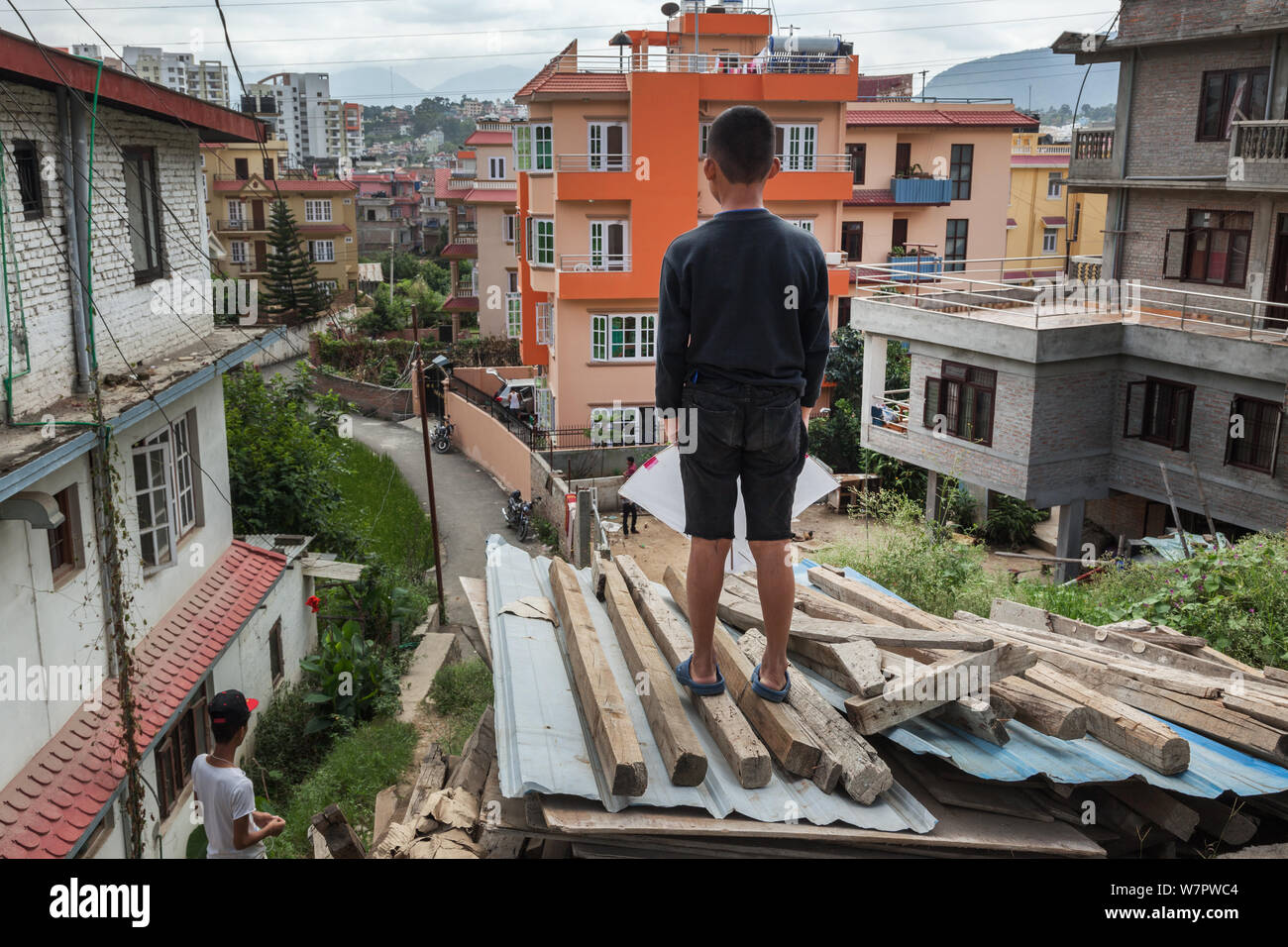 Ein Junge stehend auf einem Haufen Holz sieht eine moderne Wohn- Straße in einem Vorort von Kathmandu, Nepal Stockfoto