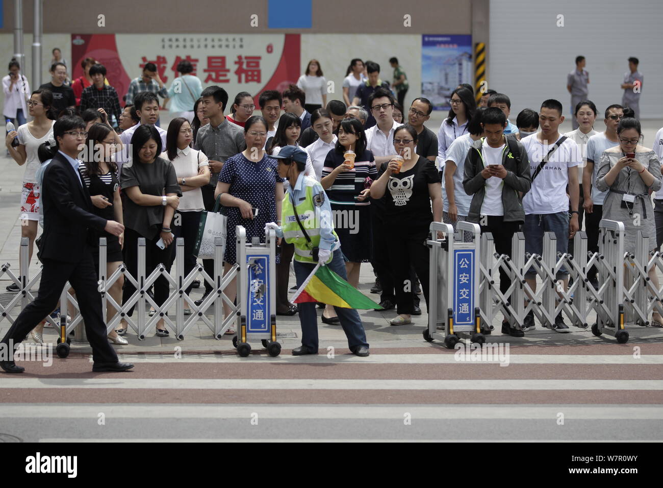 Ein Traffic Management Assistent öffnet ein Tor, damit Fußgänger die Straße überqueren, wenn die Ampel auf Grün an einer Kreuzung der Wangfujing in Beij ist Stockfoto