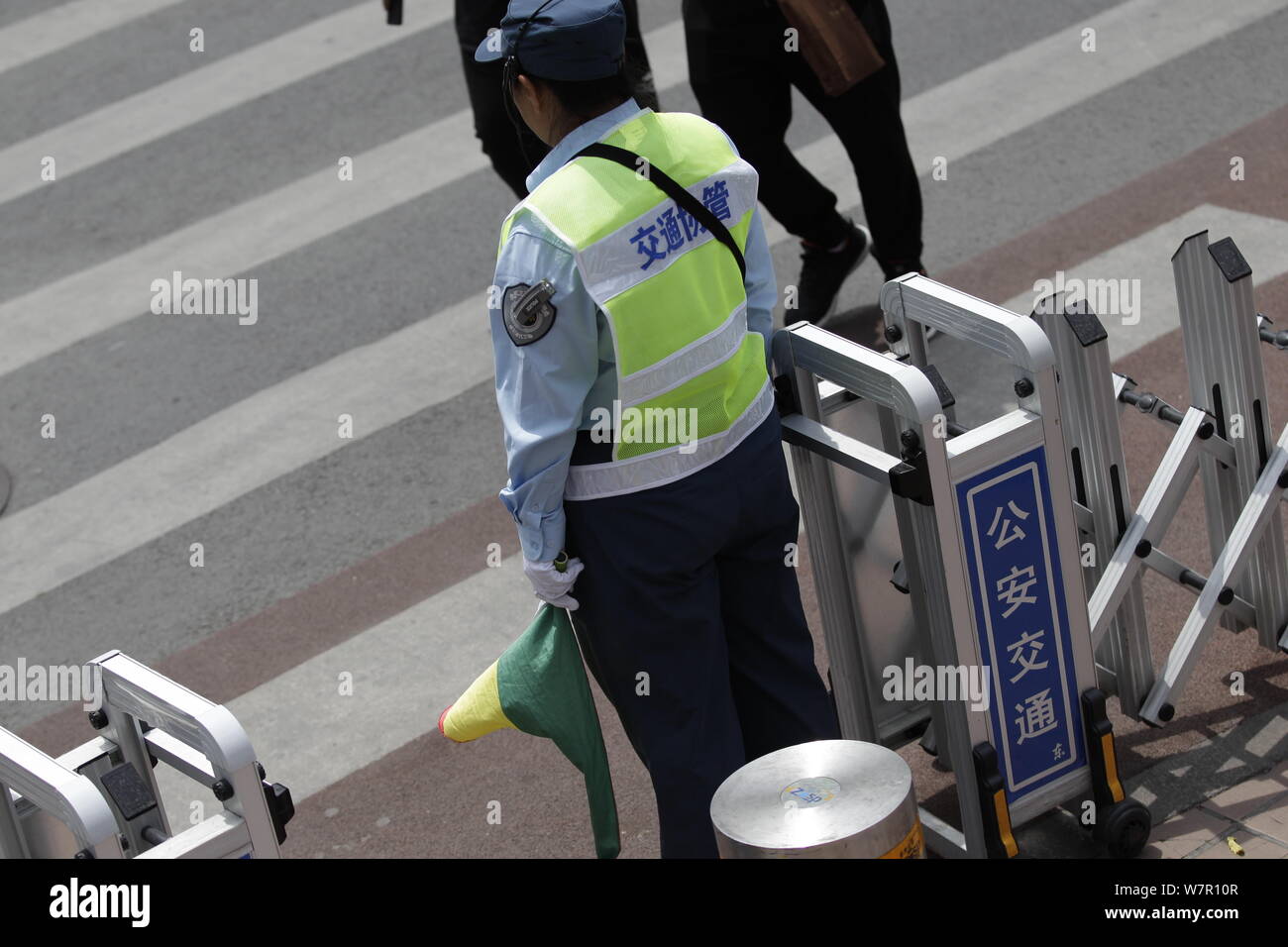 Ein Verkehr Management Assistant schließt ein Tor Fußgänger über die Straße zu überqueren, wenn die Ampel rot ist an einer Kreuzung von Wangfuj zu verhindern Stockfoto