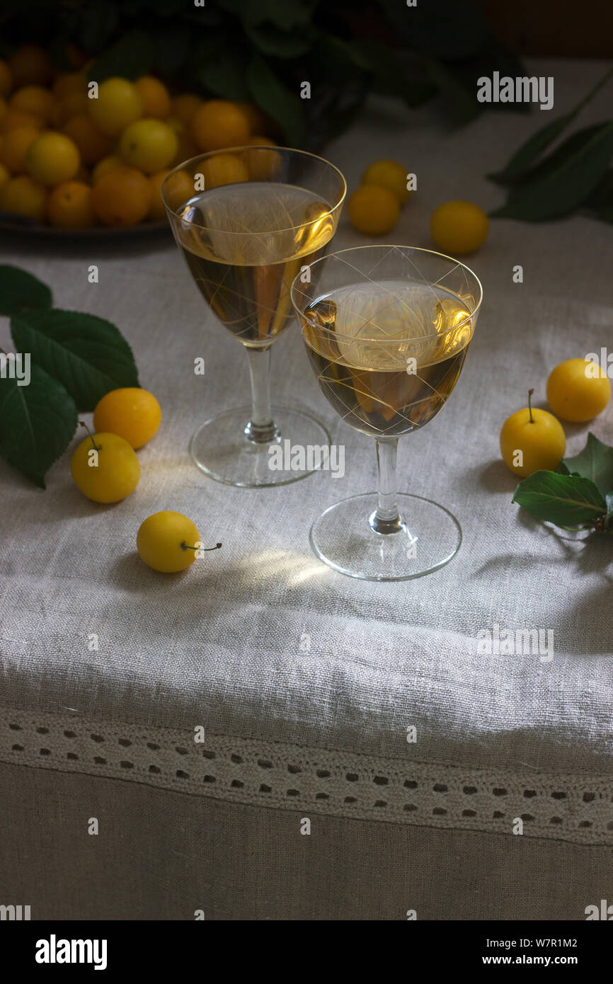 Cherry Plum Likör in kleinen Gläsern und Cherry Plum auf einer hölzernen Hintergrund. Im rustikalen Stil. Stockfoto