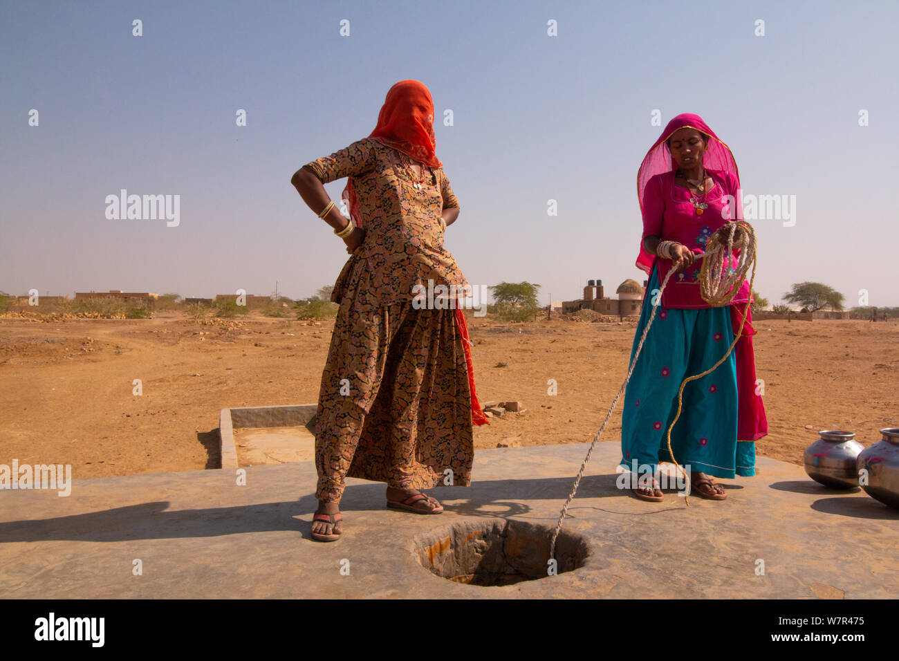 Indische Frauen in Sari in Rajasthan, holen Wasser aus der Wüste gut Stockfoto