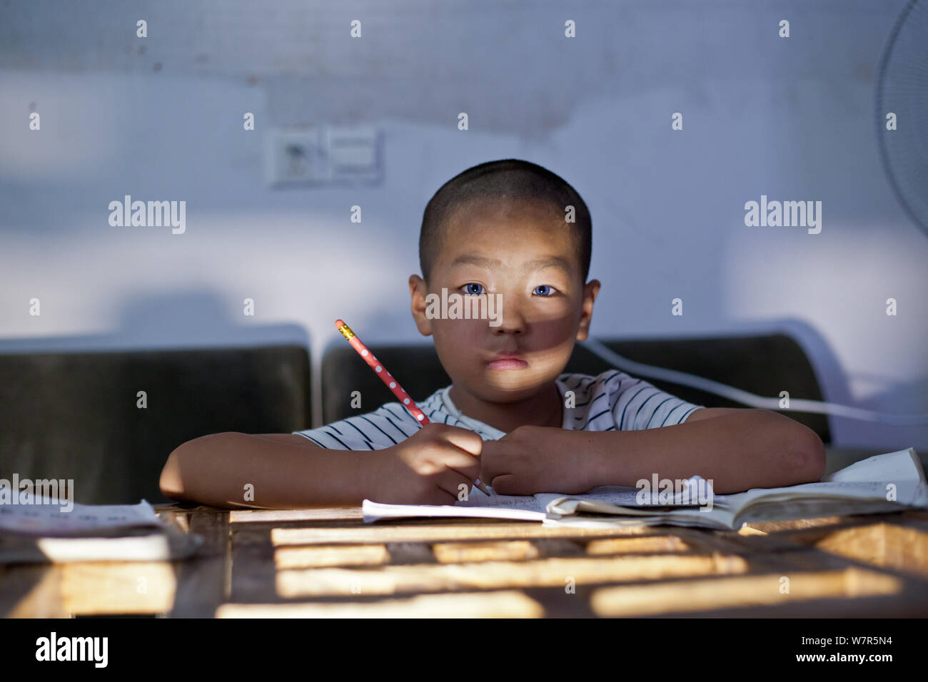 Acht-jährige Chinese Yang Shuntao, die mit blauen Augen geboren wurde und  bestimmt mit einer hochgradigen Hörverlust, macht seine Hausaufgaben in  Miluo Stadt Stockfotografie - Alamy
