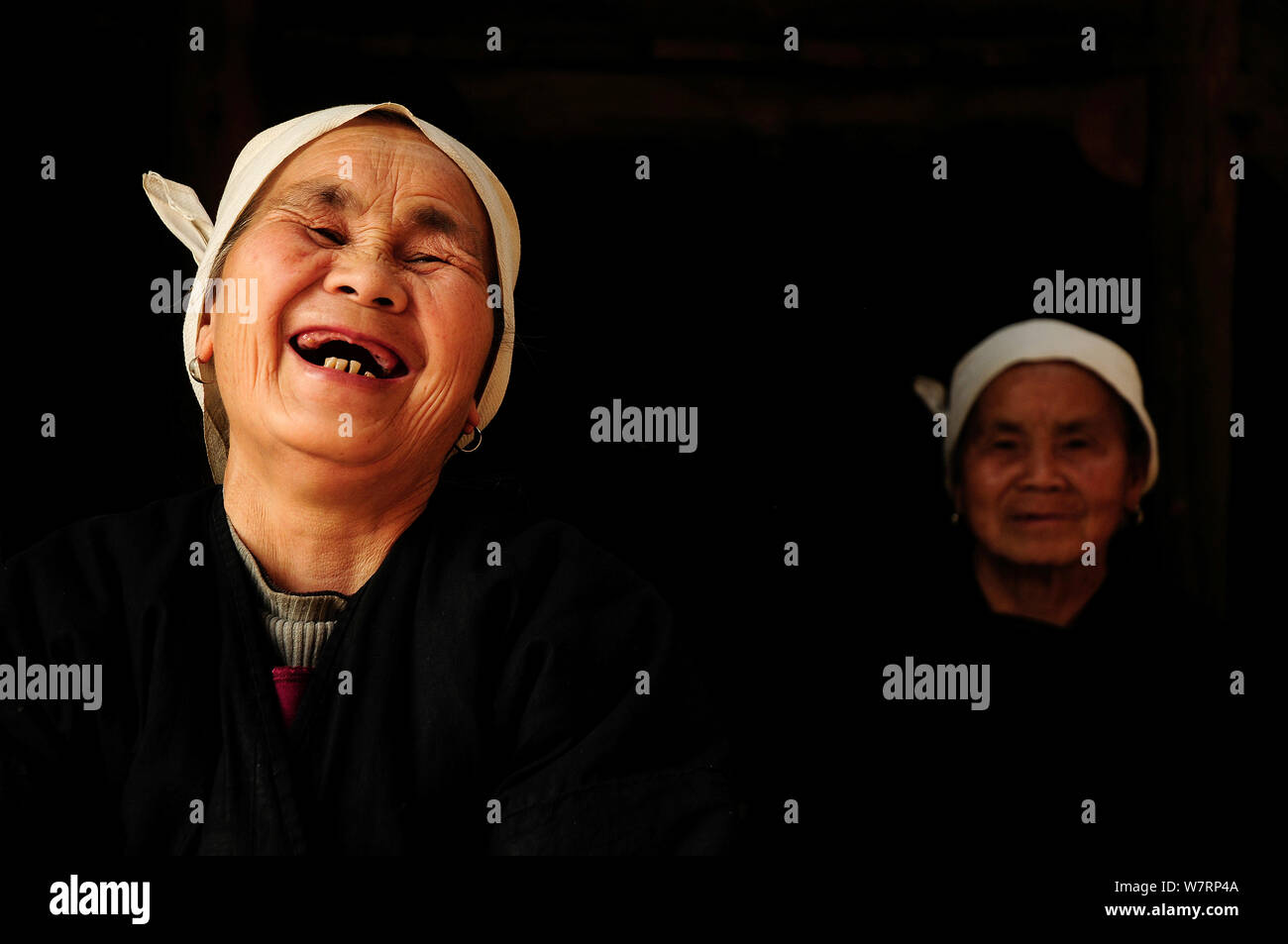 Zwei Dong Frauen, ein Lachen, in einem dunklen Zimmer, Sanjiang Dong Dorf in der Provinz Guangxi, Volksrepublik China. April 2009. Sieger der Fotograf des Jahres, Portrait Kategorie, 4 Pollux Awards, 2012 Stockfoto