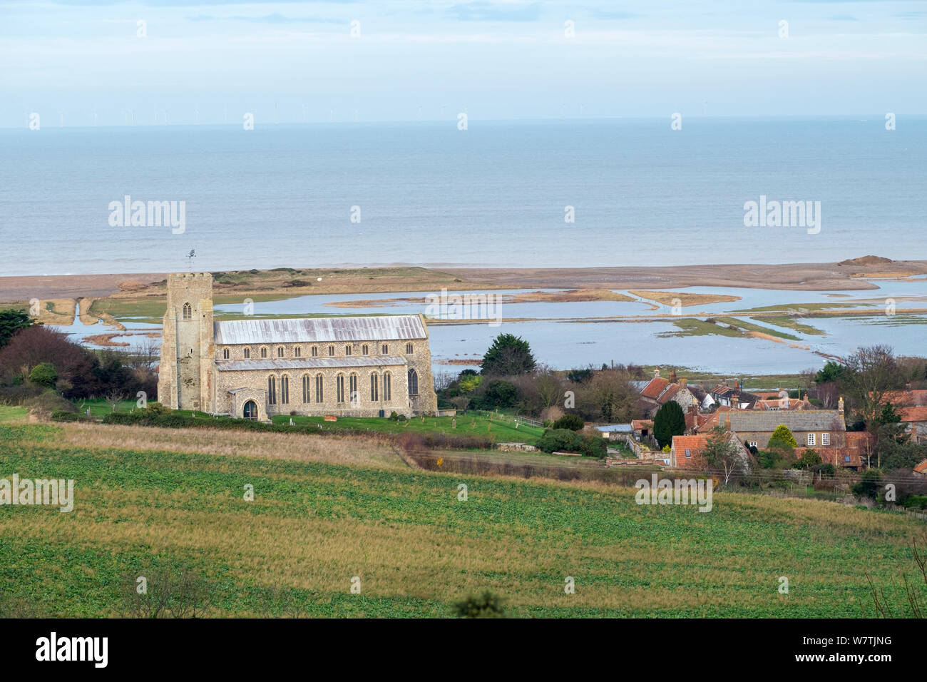 Blick Richtung St. Nicholas Kirche, mit überfluteten weiden Marsh und verletzt Schindel Küstenschutz nach dem 6. Dezember Ostküste tidal Surge im Hintergrund, Salthouse, Norfolk, England, UK, Dezember 2013. Stockfoto