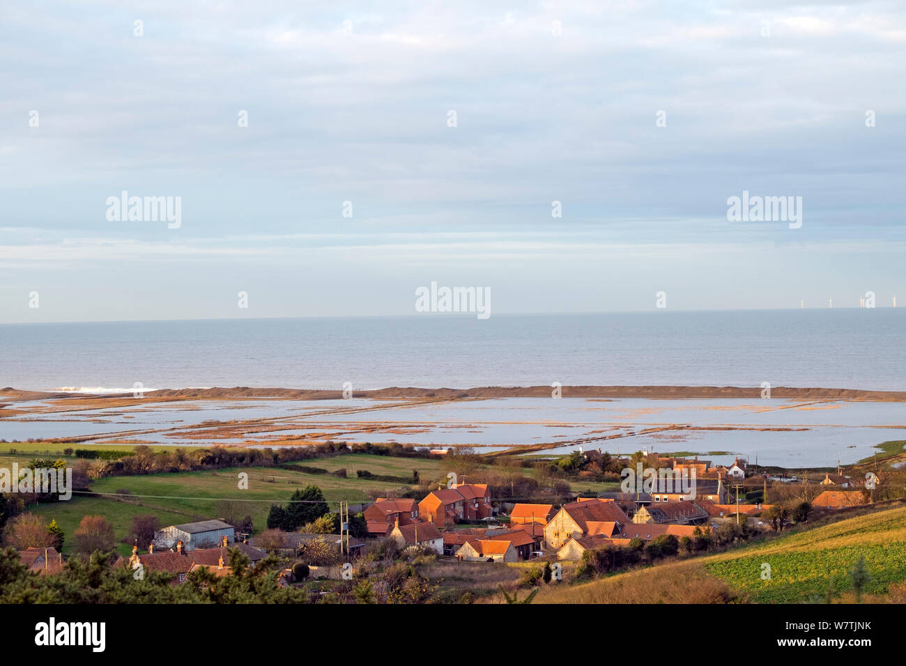 Blick auf überschwemmten Weiden Marsh und verletzt Schindel Küstenschutz nach dem 6. Dezember Ostküste tidal Surge, mit der Ortschaft Salthouse im Vordergrund, Norfolk, England, UK, Dezember 2013. Stockfoto