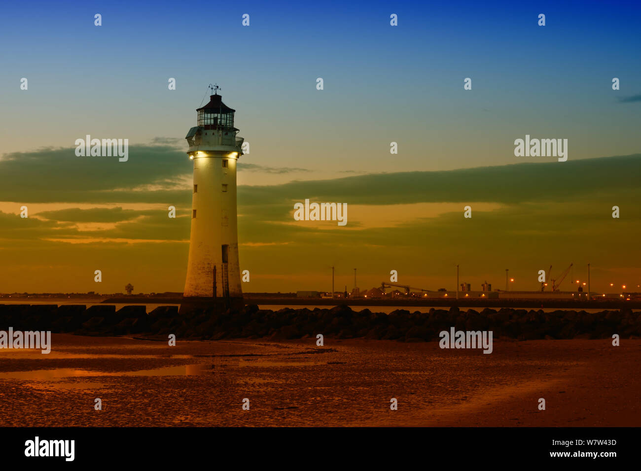 Barsch Rock Leuchtturm in New Brighton, Merseyside bei Sonnenuntergang mit Seaforth Docks in der Ferne. Stockfoto