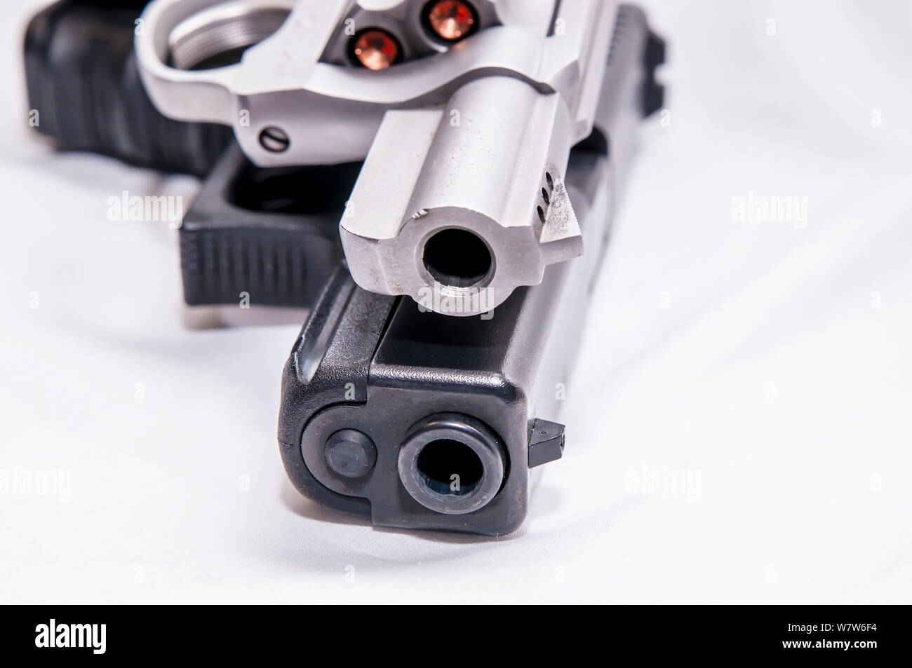 Zwei Pistolen, ein silberner snub Spitzzange 357 Magnum Revolver und ein schwarzes 9-mm-Pistole auf weißem Hintergrund Stockfoto