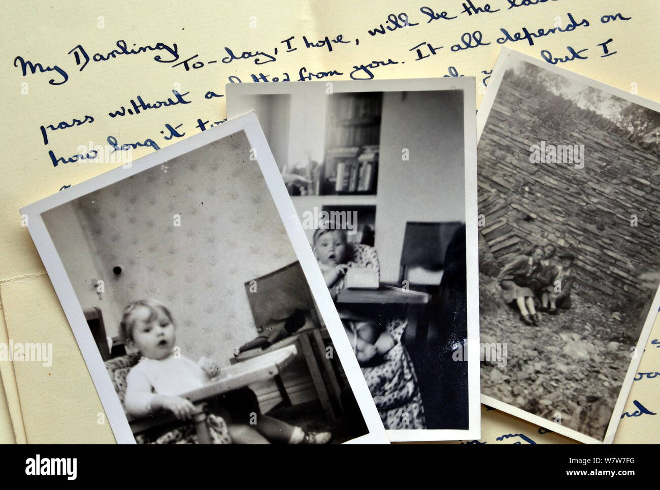 Alte Schwarzweißfotos, darunter zwei Fotos eines Babys, auf einem handschriftlichen Brief aus den alten vierziger Jahren, der beginnt: "Mein Darling". Stockfoto