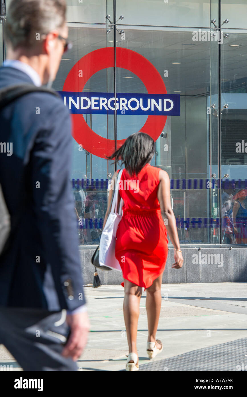 Ein Mann und eine Frau auf ihren morgendlichen Fahrt am Eingang zur U-Bahnstation Victoria, Central London. Stockfoto