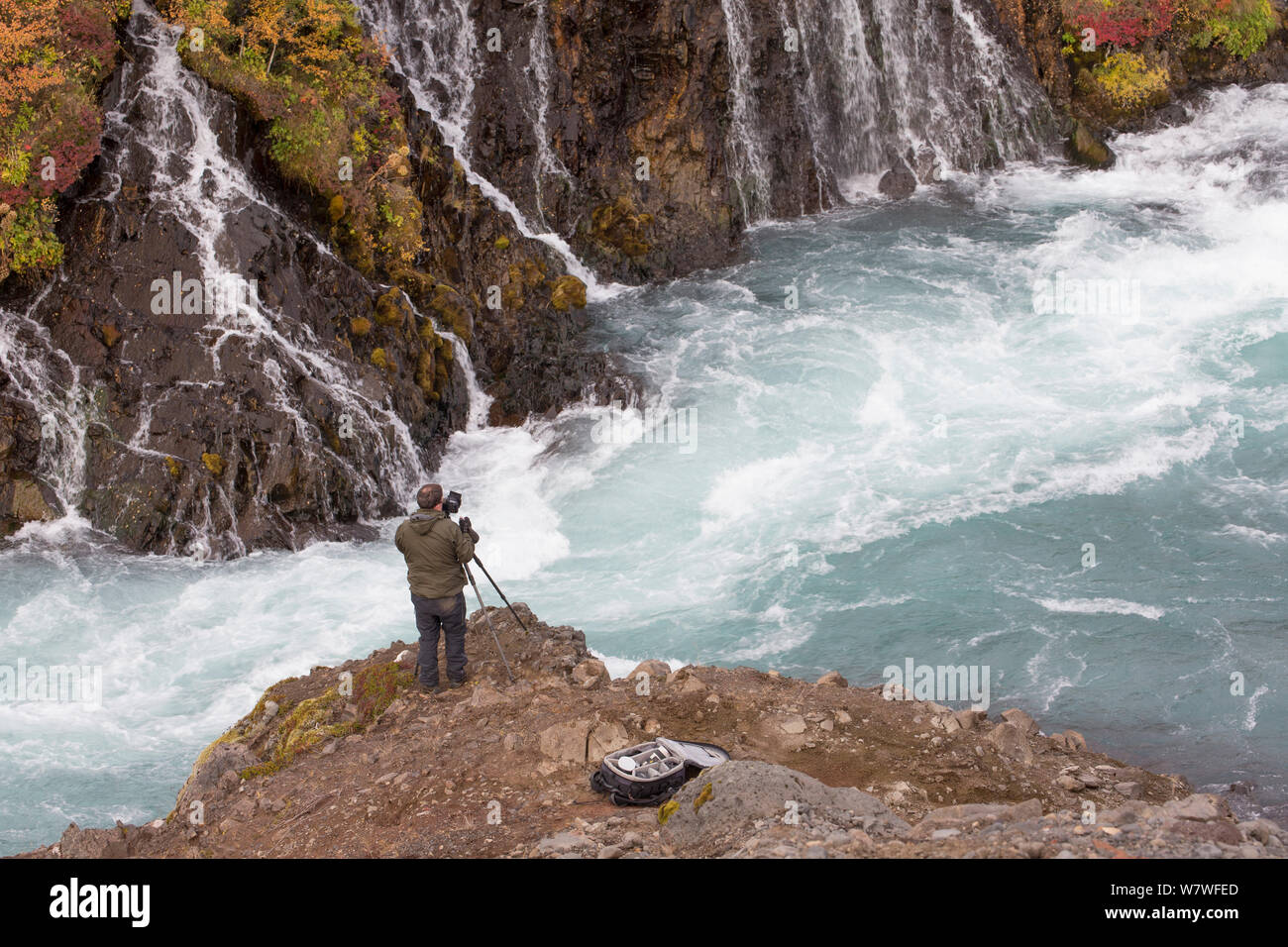 Fotograf mit Blick auf den Wasserfall und den Fluss, Wasserfällen Hraunfossar, Fluss Hvita, Island, September 2013. Stockfoto