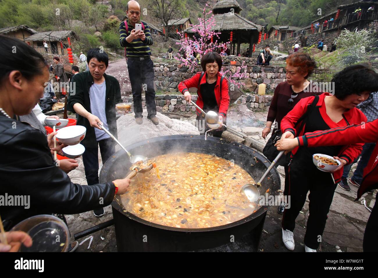 Chinesische Besucher Menge um einen großen Topf lokale Küche während einer Veranstaltung mit dem Ziel, Besucher auf den Geschmack der kleinen Stadt leben in Yugong Dorf zu geben, J zu essen Stockfoto