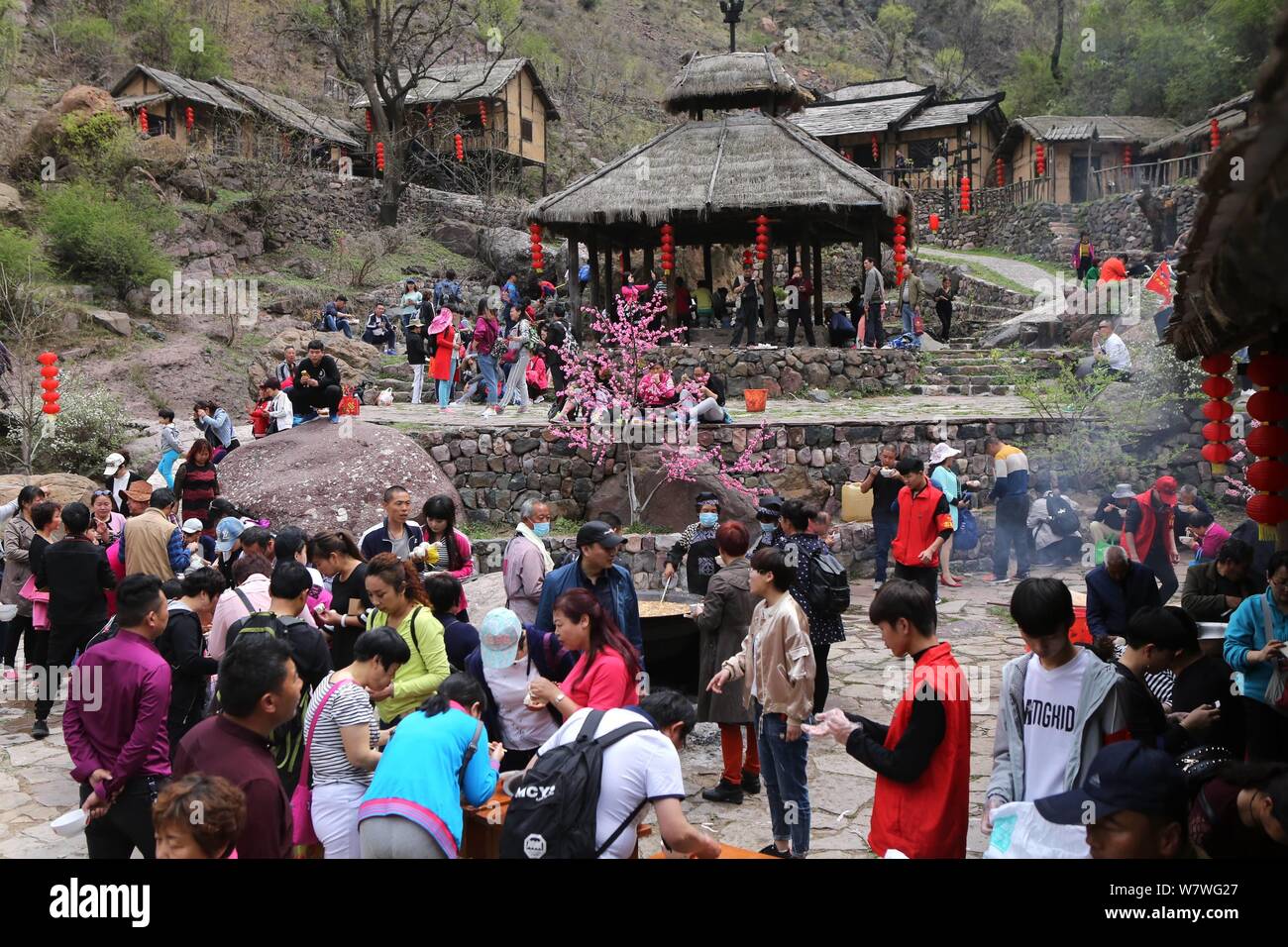 Chinesische Besucher Menge um einen großen Topf lokale Küche während einer Veranstaltung mit dem Ziel, Besucher auf den Geschmack der kleinen Stadt leben in Yugong Dorf zu geben, J zu essen Stockfoto