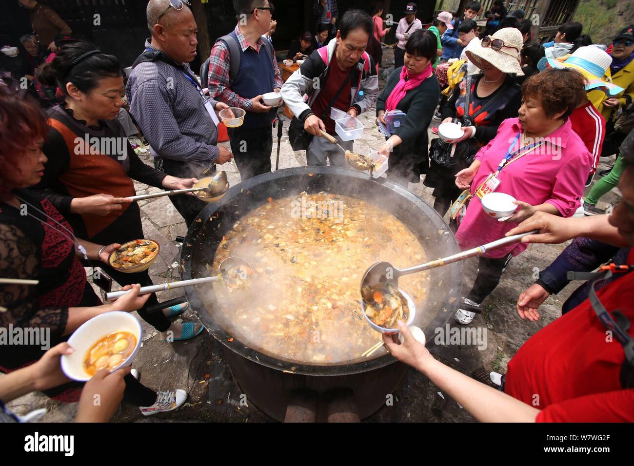 Chinesische Besucher Menge um einen großen Topf lokale Küche während einer Veranstaltung mit dem Ziel, Besucher auf den Geschmack der kleinen Stadt leben in Yugong Dorf zu geben, J zu essen Stockfoto