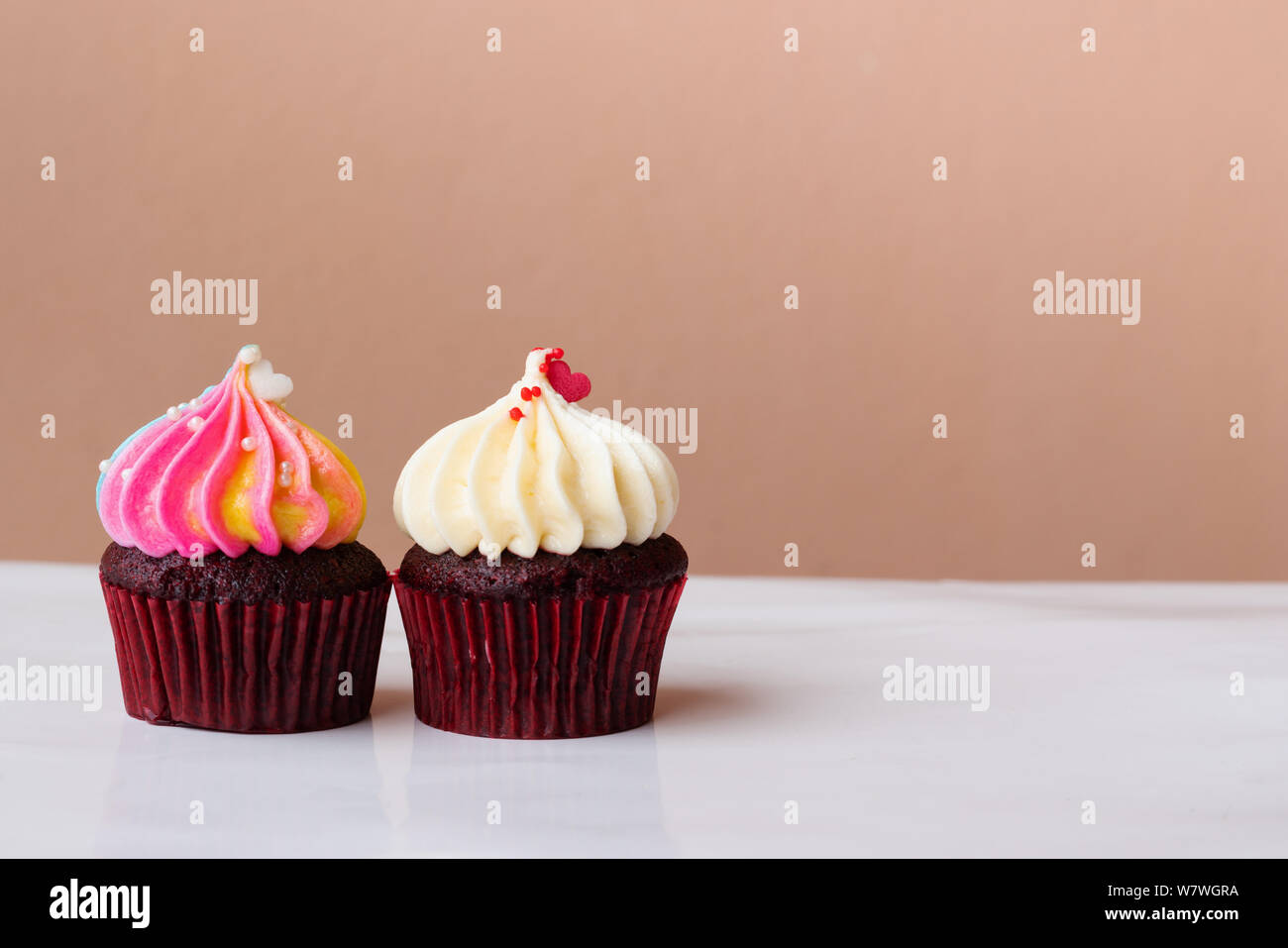 Süße Kuchen Dessert mit kleinen Herzen auf Weiß und Rainbow Creme auf rosa Hintergrund Stockfoto