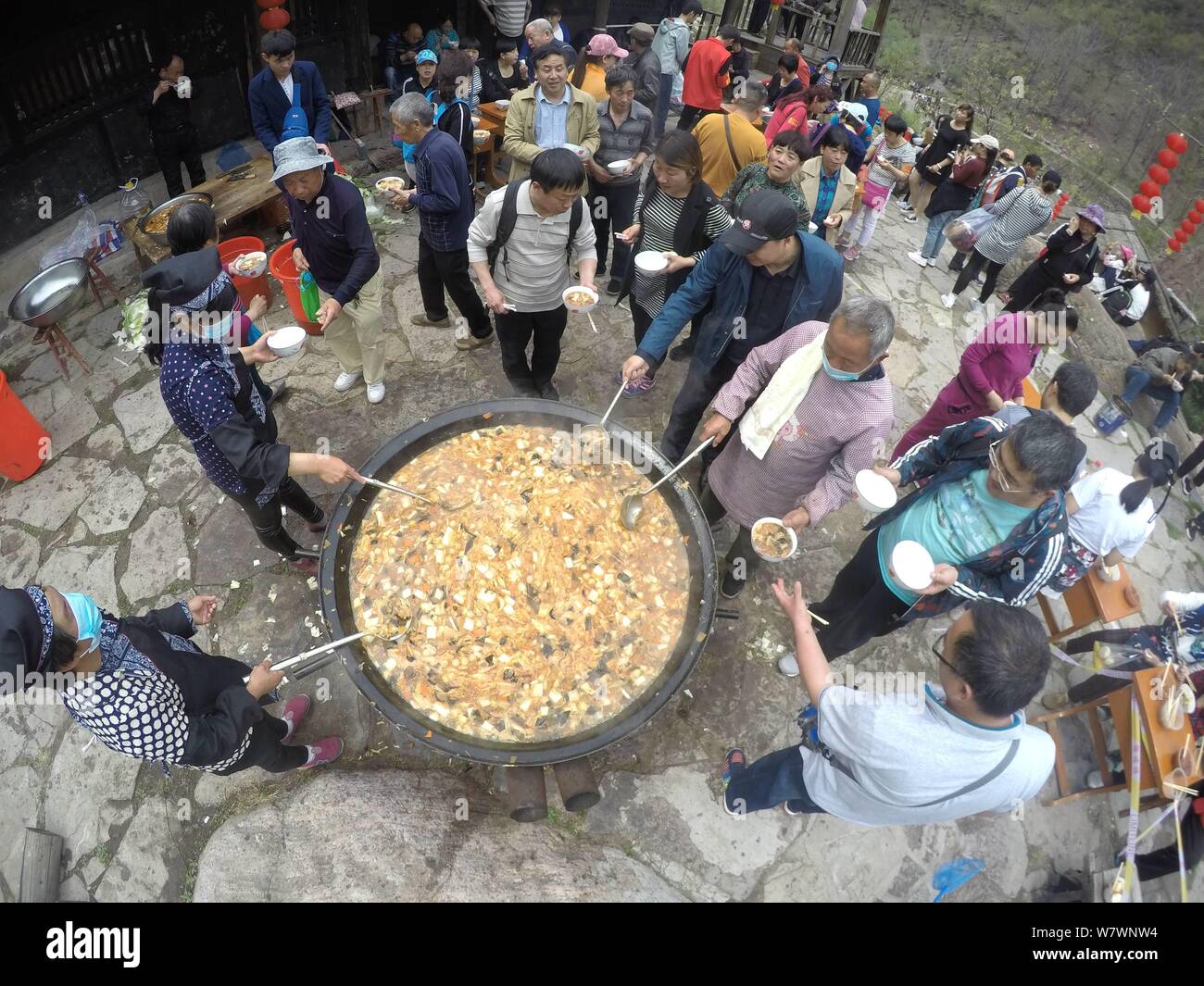 Chinesische Besucher Menge um einen großen Topf lokale Küche während einer Veranstaltung mit dem Ziel, Besucher auf den Geschmack der kleinen Stadt leben in Yugong Dorf zu geben, J zu essen Stockfoto