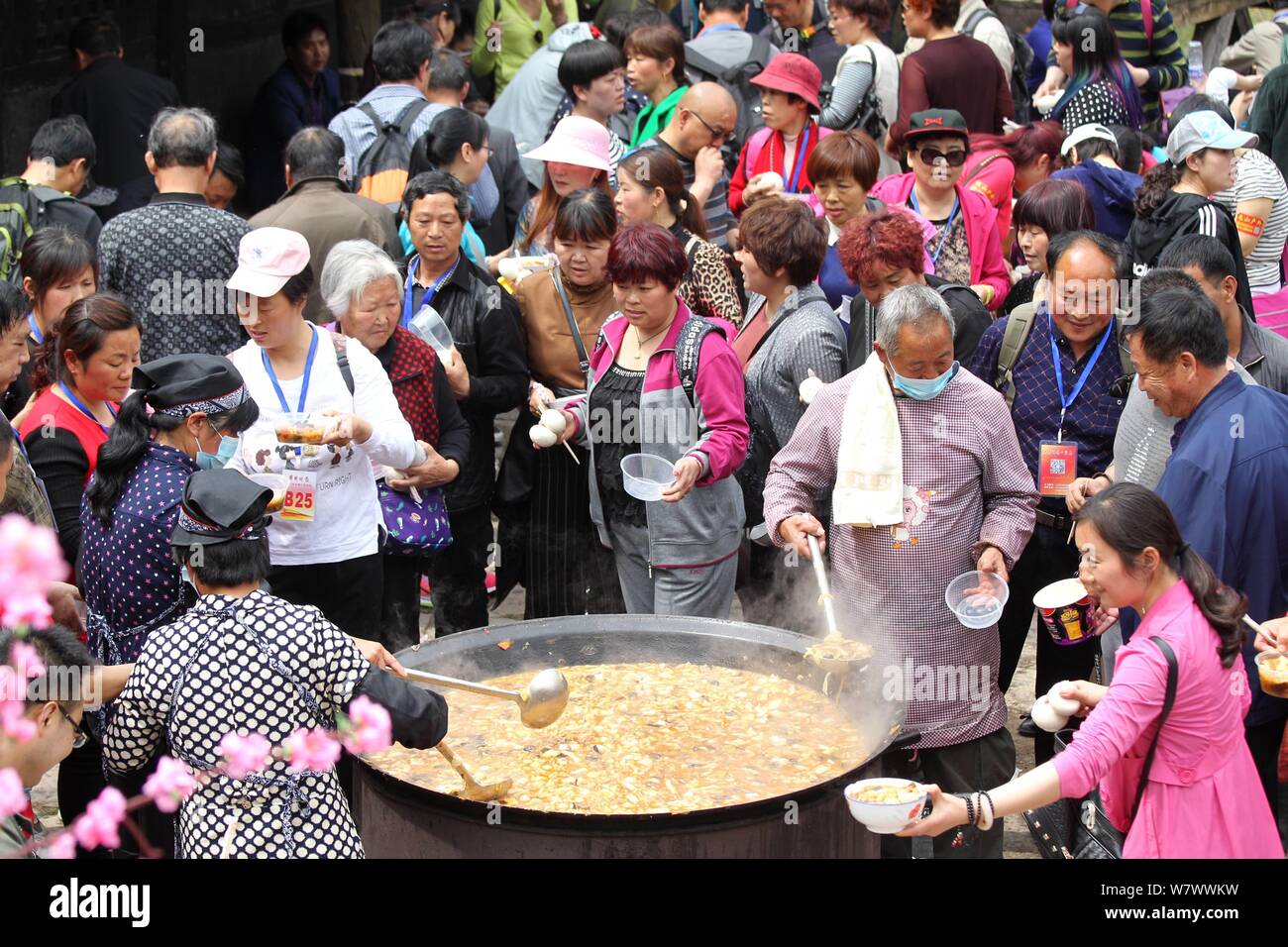 Chinesische Besucher Menge um einen großen Topf lokale Küche während einer Veranstaltung mit dem Ziel, Besucher auf den Geschmack der kleinen Stadt leben in Yugong Dorf zu geben, J zu essen Stockfoto