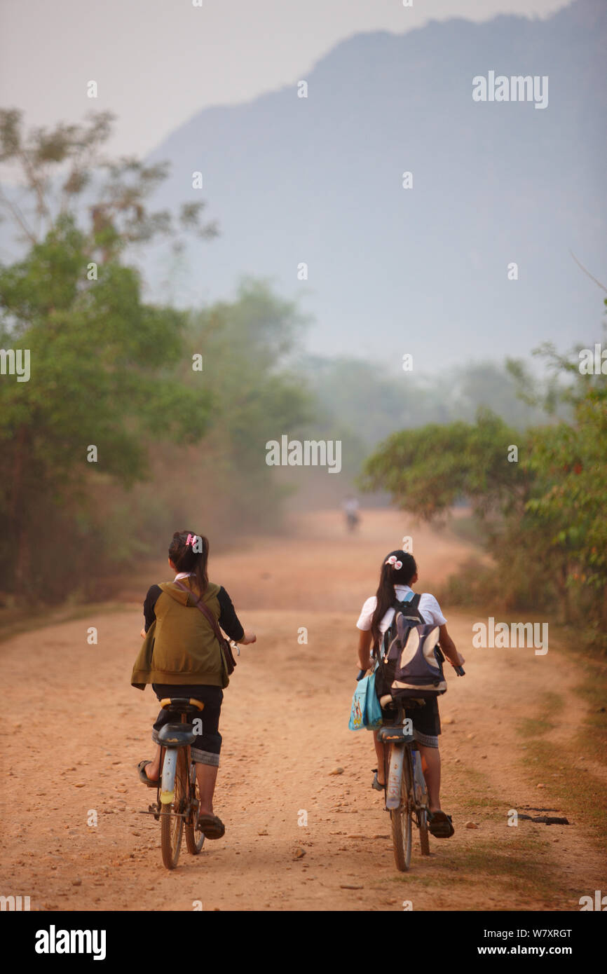 Kinder Radfahren zur Schule, in der Nähe von Vang Vieng, Laos, März 2009. Stockfoto