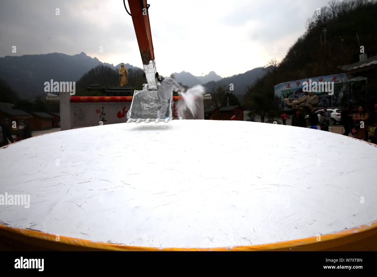 Ein Bäcker von einem Bagger setzt das i-Tüpfelchen auf einem riesigen Kuchen der 2.588 Geburtstag des Gründers des Taoismus Lao Zi (Laotse) auf Laoj zu feiern. Stockfoto