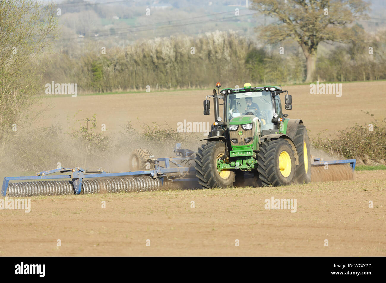 Buckingham, Großbritannien - 01 April, 2019. Ein Bauer fährt ein John Deere Traktor Land während einer Dürre zu kultivieren, mit einem Cambridge Walze oder cultipacker. Stockfoto Buckingham, Großbritannien - 01 April, 2019. Ein Bauer fährt ein John Deere Traktor Land während einer Dürre zu kultivieren, mit einem Cambridge Walze oder cultipacker. Stockfoto