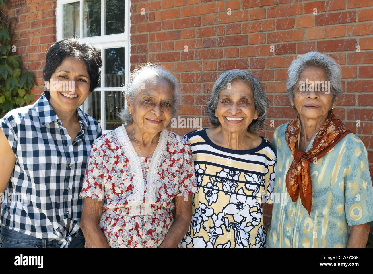Buckingham, Großbritannien - 05.Juli 2019. Drei ältere indische Frauen stellen mit einer Tochter lächelnd für ein ehrliches Porträt an einer Wiedervereinigung in Großbritannien. Stockfoto