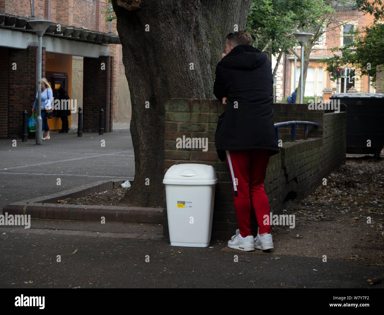 Mann, der mit einem Plastikbehälter vor einem Supermarkt wartet Stockfoto
