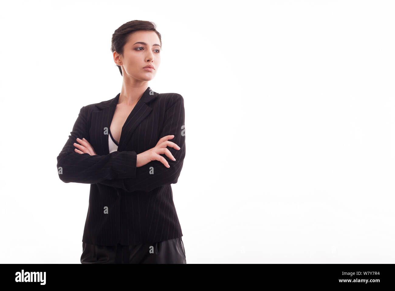 Schöne junge Mädchen in schwarzen Jacke mit Hände gekreuzt entfernt Blick auf weißen Hintergrund. Kopieren Sie Speicherplatz zur Verfügung. Modernes Outfit. Stockfoto