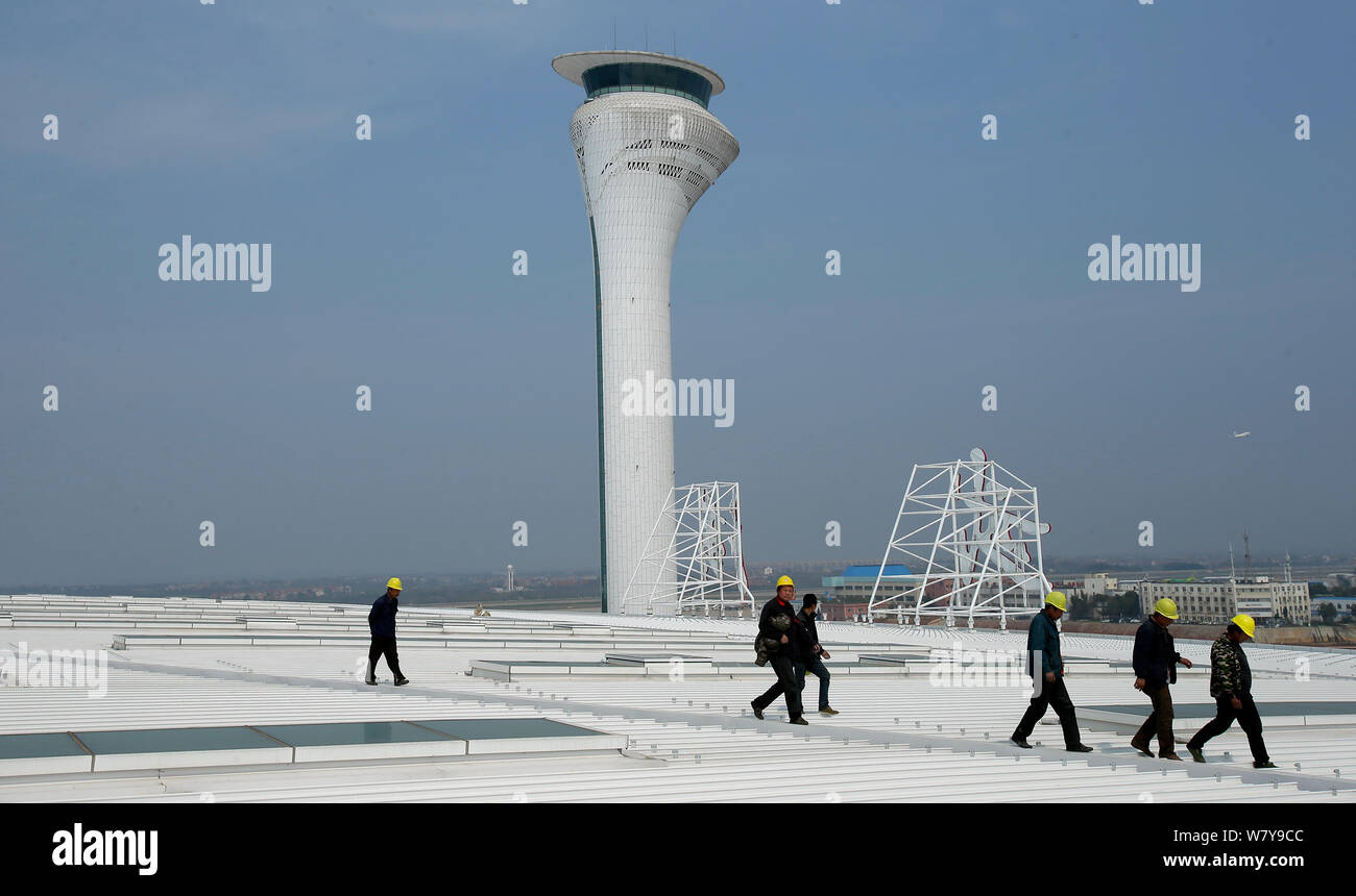 Chinesische Arbeiter vorbei an der Flugverkehrskontrolle am Terminal 3 Gebäude am internationalen Flughafen Wuhan Tianhe in Wuhan City, Central China" Stockfoto