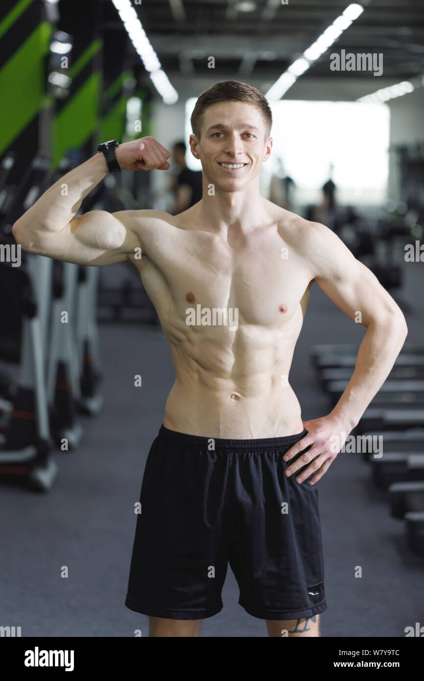 Portrait von Sportler mit perfekten Körper stehend an der Turnhalle nach dem Workout und zeigt seinen Bizeps Stockfoto