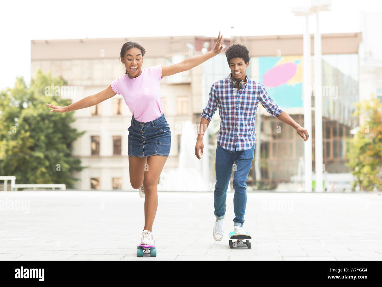 Happy teenage Paar reiten modernen Cruiser Skateboards auf Stadt. Stockfoto