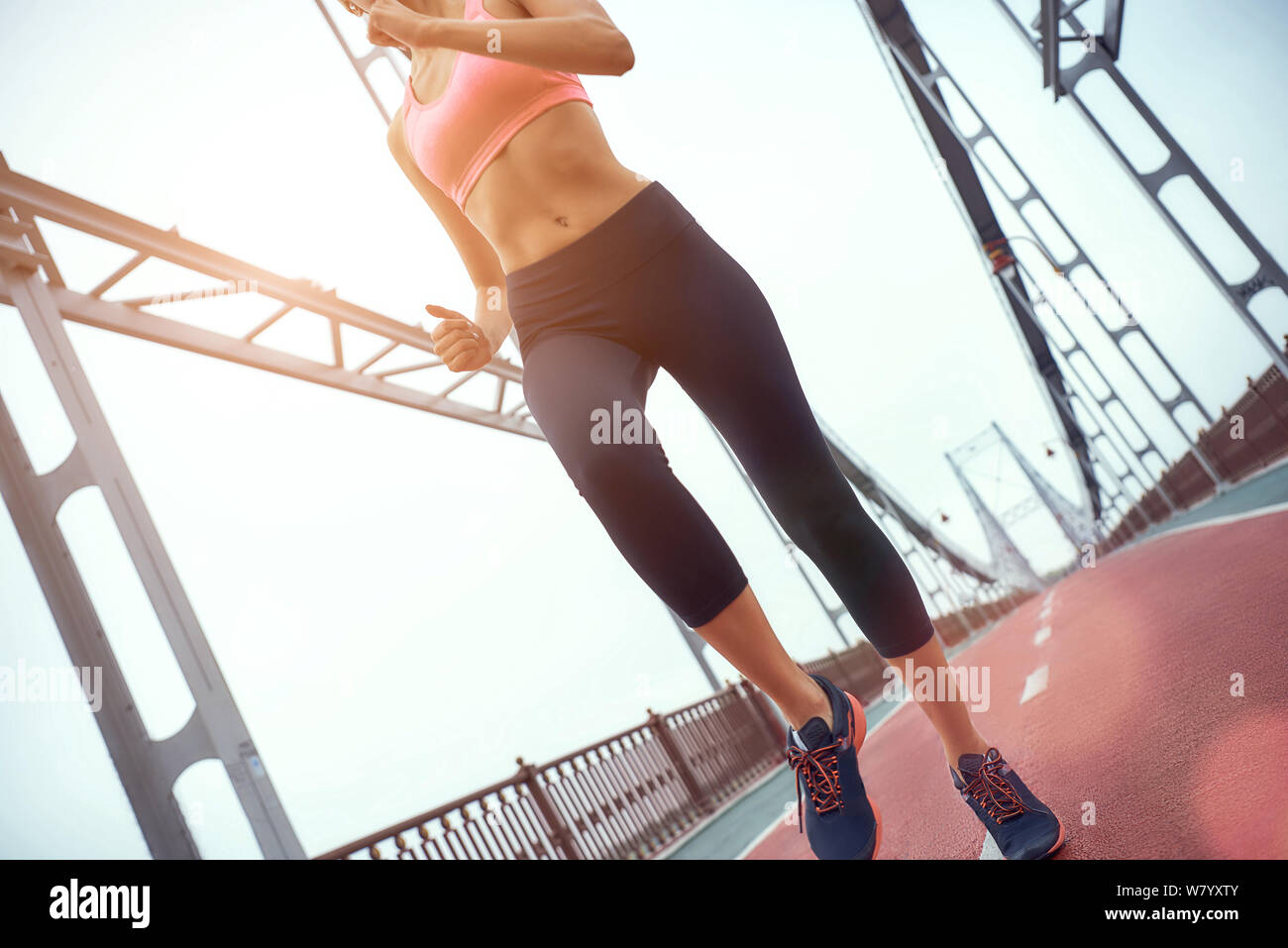 Nicht denken. Ausführen. Junge und schlanke Frau in Sportbekleidung Jogging auf der Brücke. Sport Konzept. Gesunder Lebensstil Stockfoto