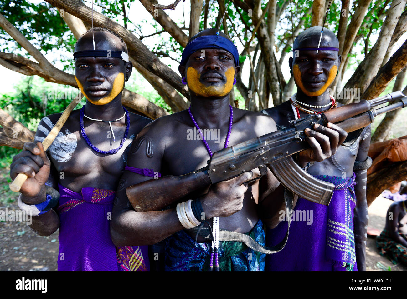 Mursi Dorf, bewaffnete Männer mit traditioneller Kleidung und Schmuck. Mursi Stamm. Mago National Park. Äthiopien, November 2014 Stockfoto