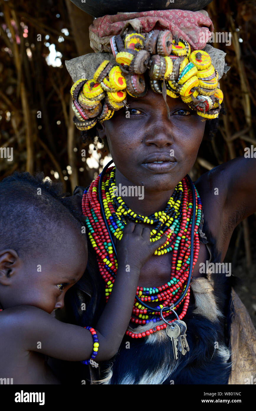 Dassanech Frau mit Kind, in der traditionellen Kleidung, mit Kopfschmuck aus Bottlecaps, untere Omo Tal. Äthiopien, November 2014 Stockfoto