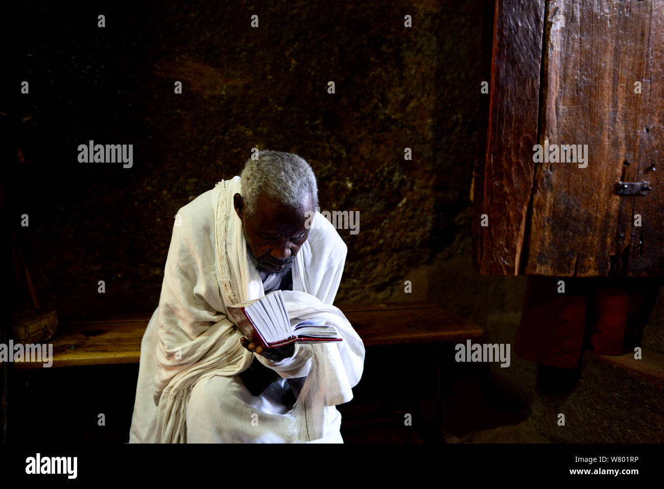 Priester Lesen der Bibel in Wette Maryam Kirche (Teil der nordwestlichen Gruppe von Kirchen in Lalibela). UNESCO-Weltkulturerbe. Lalibela. Äthiopien, Dezember 2014. Stockfoto