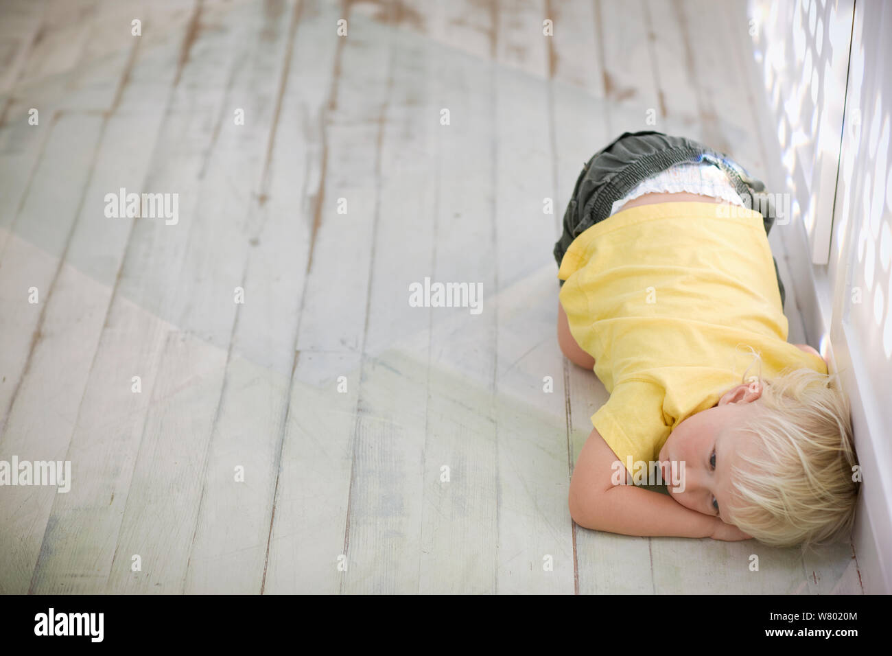 Junge zusammengerollt auf dem Boden. Stockfoto