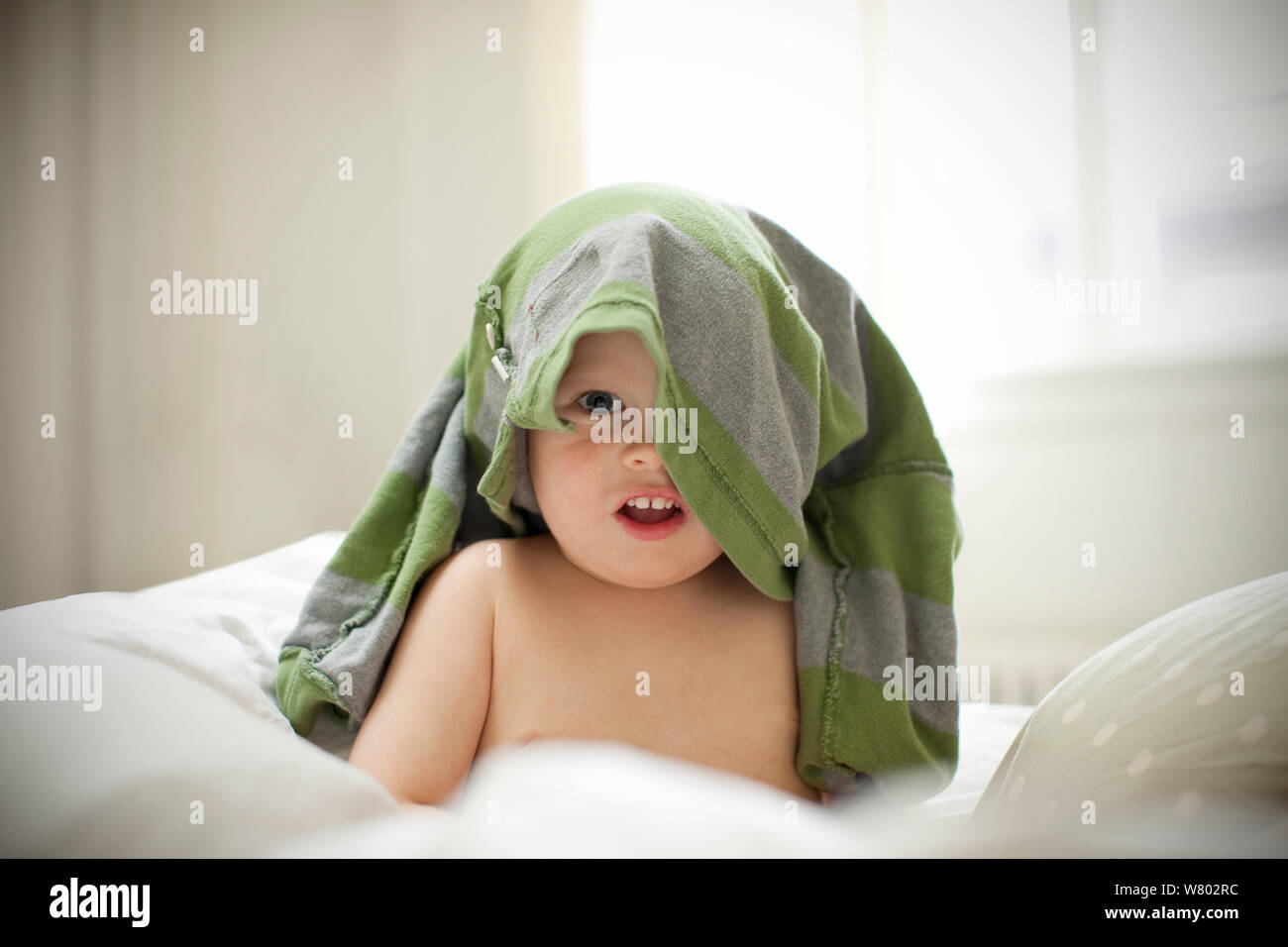 Portrait einer jungen Kleinkind sitzen mit einem T-Shirt über seinen Kopf. Stockfoto