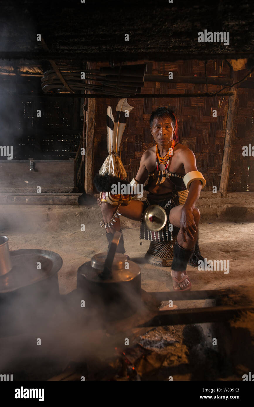 Chang Naga Mann in festival Dres im Haus; Tiger Claws (Panthera tigris) um sein Gesicht, Nashornvogel (Bucerotidae) Federn am Hut, und aus den Stoßzähnen (Sus scrofa) am Hut. Chang Naga Mann headhunting Stamm. Tuensang Bezirk. Nagaland, North East India, Oktober 2014. Stockfoto