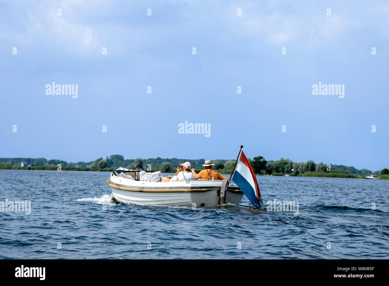 Touristen genießen die Fahrt in der weißen Luxury Motor Yacht mit niederländischer Flagge. Sommer Urlaub oder ein Boot mieten. Stockfoto